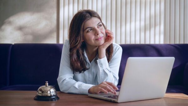 Gestora analisando demanda previsível na hotelaria pelo notebook para reduzir os efeitos da sazonalidade